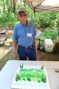 Dave Cruickshank poses in front of a cake commemorating the 60th running of the Cruickshank Woodland Tour for 5th graders.